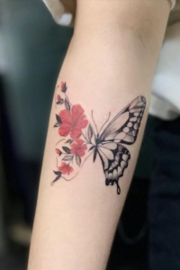 red ink and black ink butterfly tattoo on a forearm