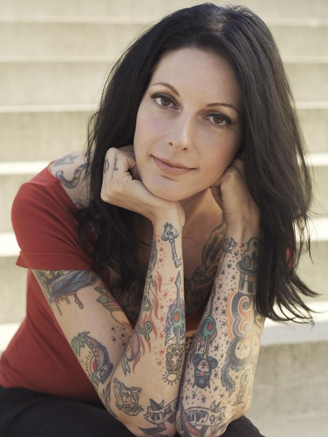 woman looking at camera with tattoos on her arms