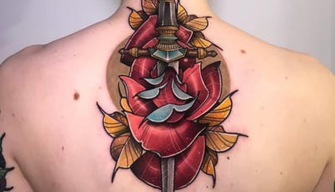 large upper back tattoo of dagger and rose